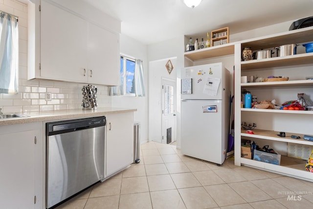 kitchen with light tile patterned flooring, white cabinetry, dishwasher, white fridge, and decorative backsplash