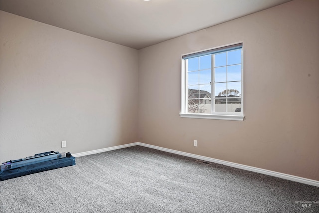 unfurnished room with carpet, visible vents, and baseboards