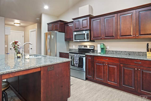 kitchen with light stone counters, recessed lighting, light wood-style flooring, appliances with stainless steel finishes, and a sink