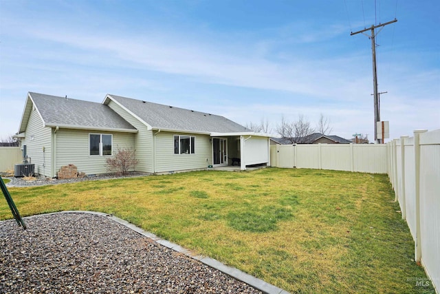 back of house with roof with shingles, central AC unit, a lawn, and a fenced backyard