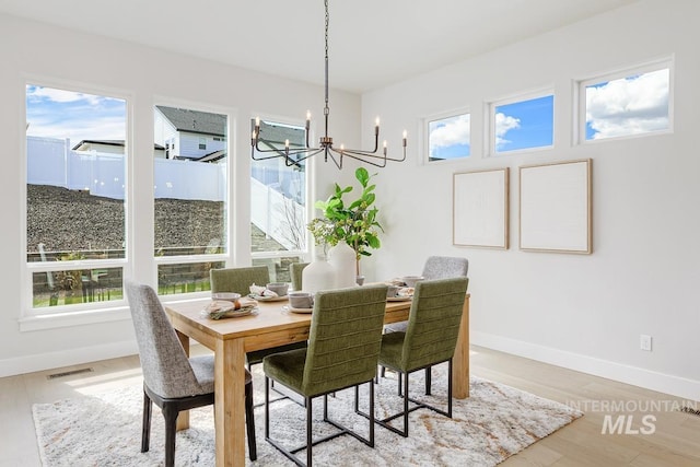 dining room featuring baseboards, wood finished floors, a notable chandelier, and visible vents