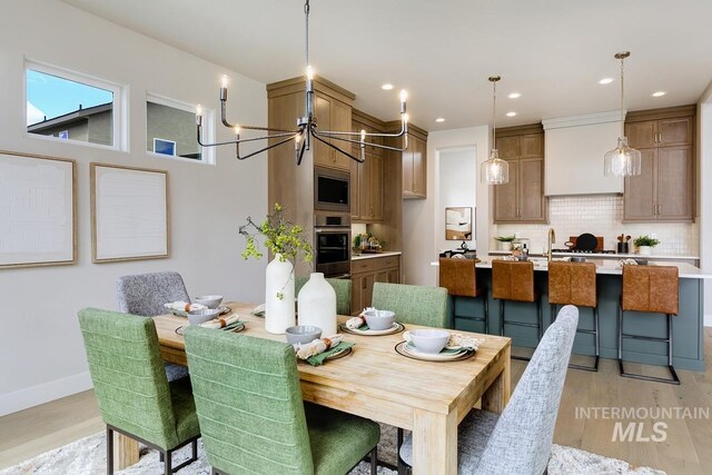 dining room with recessed lighting, light wood-style flooring, baseboards, and an inviting chandelier