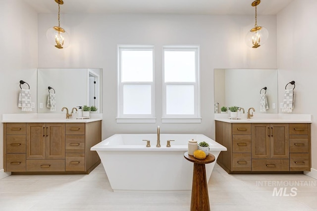 full bath with a freestanding bath, two vanities, and a sink