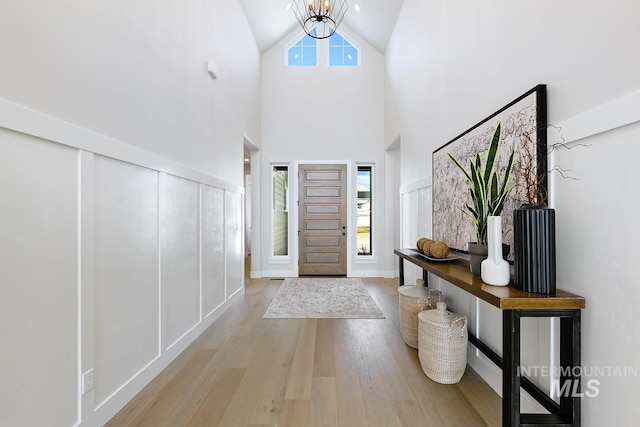 entryway featuring high vaulted ceiling, a notable chandelier, and wood finished floors