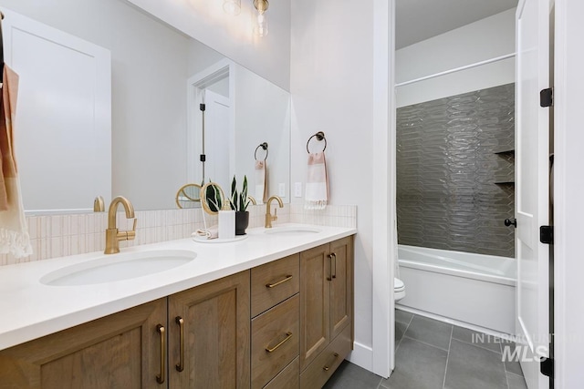 full bath with a sink, toilet, double vanity, and tile patterned flooring