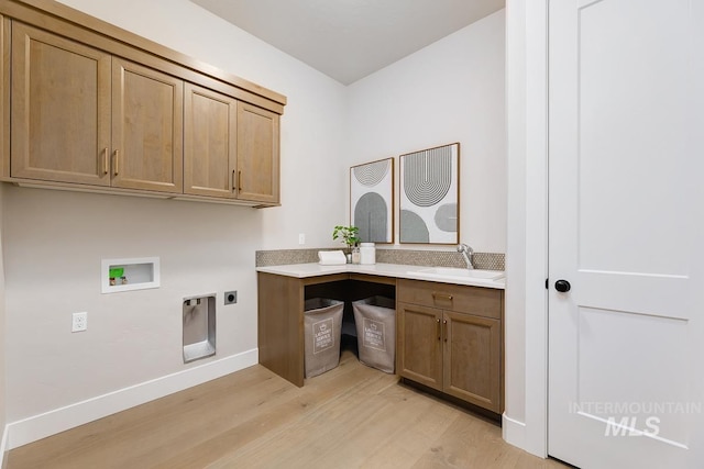 washroom with a sink, light wood-type flooring, hookup for an electric dryer, cabinet space, and hookup for a washing machine