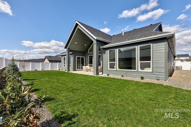 back of property featuring central AC, a fenced backyard, a lawn, roof with shingles, and a patio area