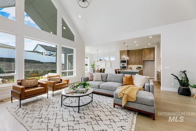 living area featuring light wood-style floors, high vaulted ceiling, visible vents, recessed lighting, and baseboards