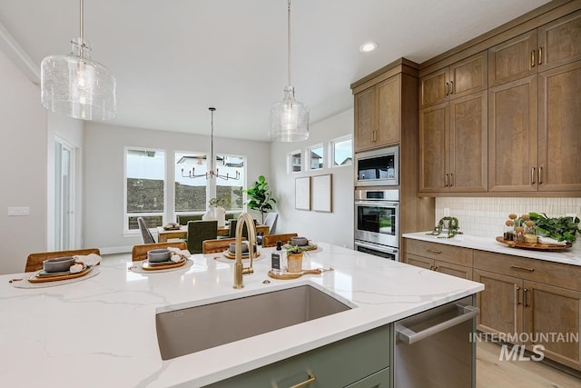 kitchen featuring stainless steel appliances, tasteful backsplash, a sink, and hanging light fixtures