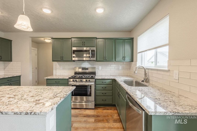 7666 E Lightfoot St, Nampa, ID 83687 - kitchen featuring appliances with stainless steel finishes, green cabinets, a sink, wood finished floors, and a textured ceiling