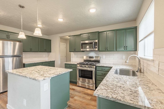 7666 E Lightfoot St, Nampa, ID 83687 - kitchen featuring stainless steel appliances, green cabinets, a sink, light wood-style floors, and a textured ceiling