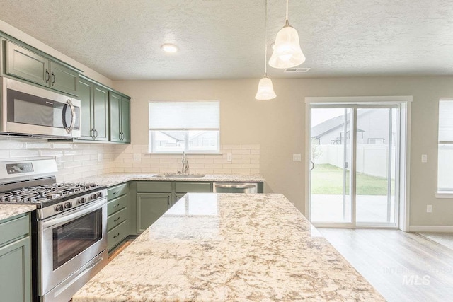 7666 E Lightfoot St, Nampa, ID 83687 - kitchen featuring stainless steel appliances, green cabinets, a sink, a textured ceiling, and decorative backsplash