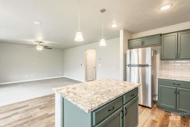 7666 E Lightfoot St, Nampa, ID 83687 - kitchen with freestanding refrigerator, a textured ceiling, a ceiling fan, decorative light fixtures, and light wood-type flooring