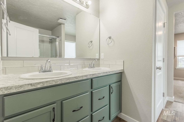 7666 E Lightfoot St, Nampa, ID 83687 - bathroom with a textured ceiling, double vanity, a shower stall, baseboards, and wood finished floors