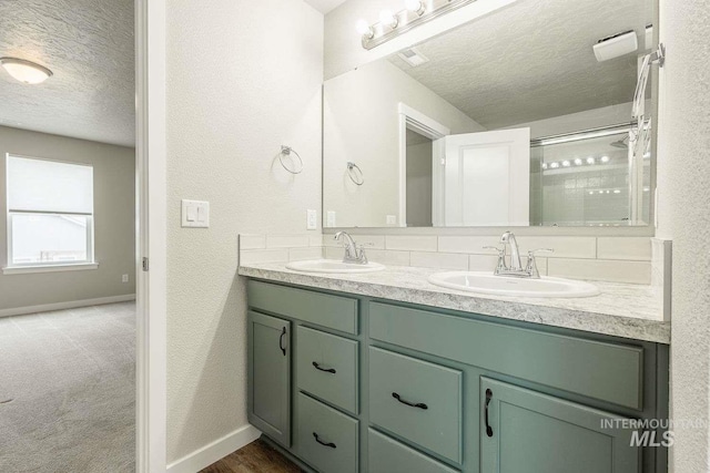 7666 E Lightfoot St, Nampa, ID 83687 - bathroom featuring a textured ceiling, double vanity, a textured wall, baseboards, and a shower