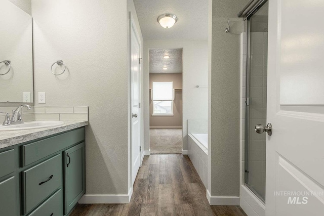 7666 E Lightfoot St, Nampa, ID 83687 - full bath with wood finished floors, vanity, a shower with shower door, a tub, and baseboards