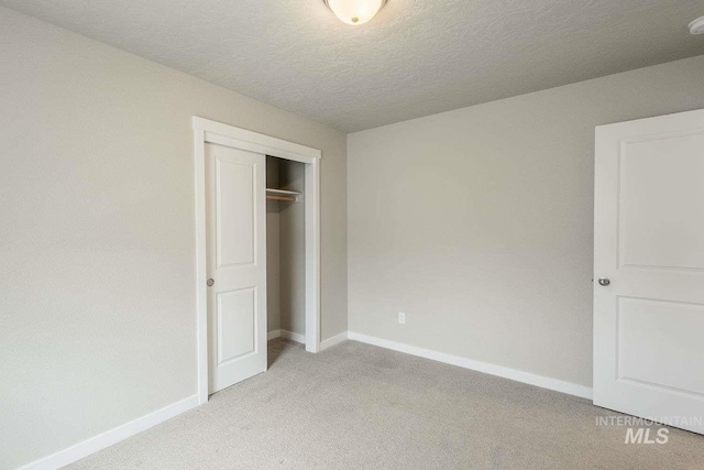 7666 E Lightfoot St, Nampa, ID 83687 - unfurnished bedroom with light carpet, baseboards, a closet, and a textured ceiling
