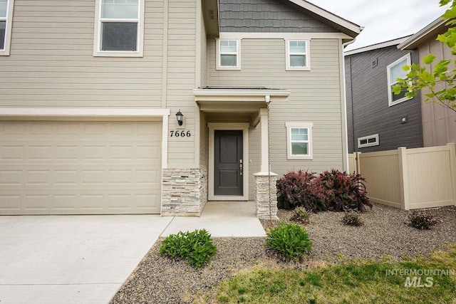 7666 E Lightfoot St, Nampa, ID 83687 - view of front of property with fence, a garage, driveway, and stone siding