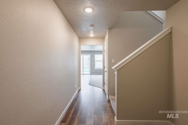 7666 E Lightfoot St, Nampa, ID 83687 - hallway with dark wood-type flooring, baseboards, a textured wall, a textured ceiling, and stairs