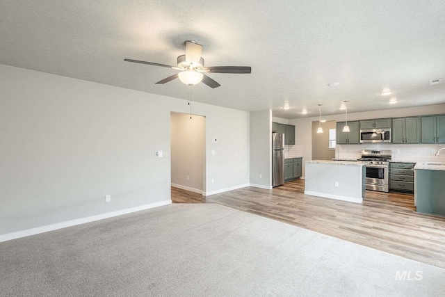 7666 E Lightfoot St, Nampa, ID 83687 - unfurnished living room with baseboards, ceiling fan, light colored carpet, light wood-style floors, and a textured ceiling