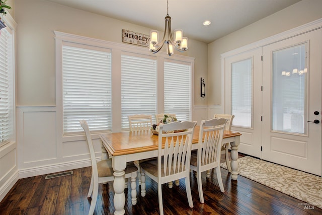 dining room with dark wood-type flooring and a chandelier