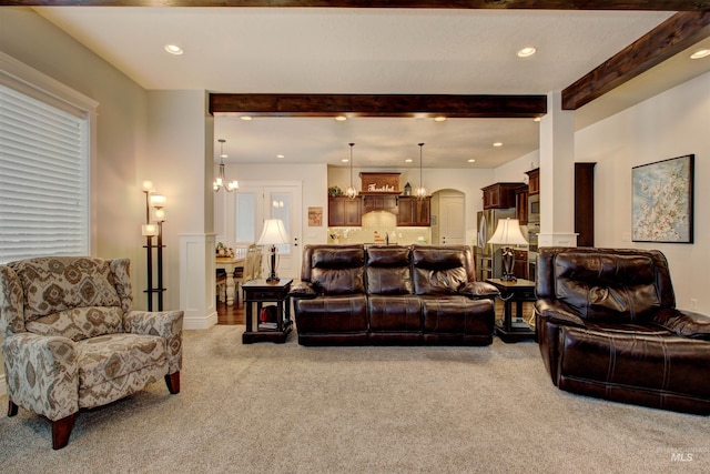 carpeted living room with a chandelier and beam ceiling