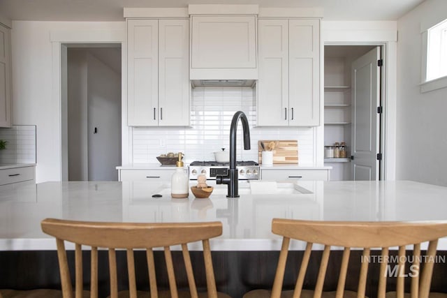 kitchen featuring light countertops, backsplash, and white cabinetry