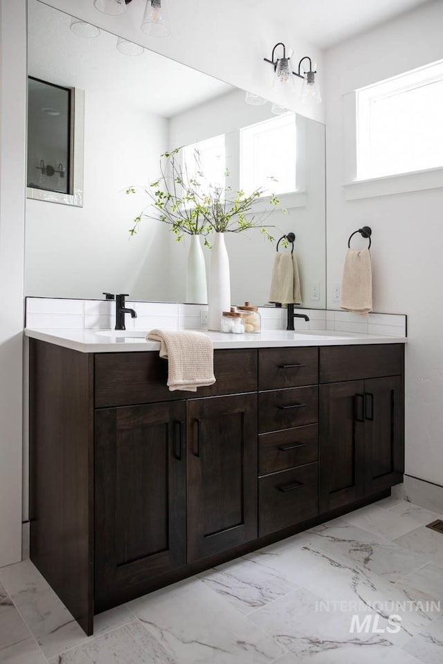 bathroom featuring double vanity, marble finish floor, and a sink