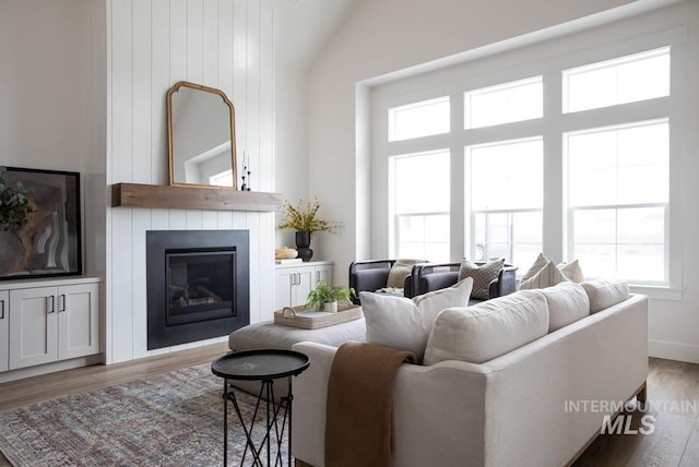 living area featuring high vaulted ceiling, a fireplace, and light wood-style floors