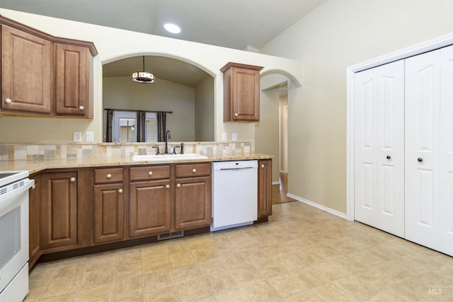 421 N David Frost St, Nampa, ID 83651 - kitchen featuring white appliances, a sink, arched walkways, vaulted ceiling, and brown cabinetry