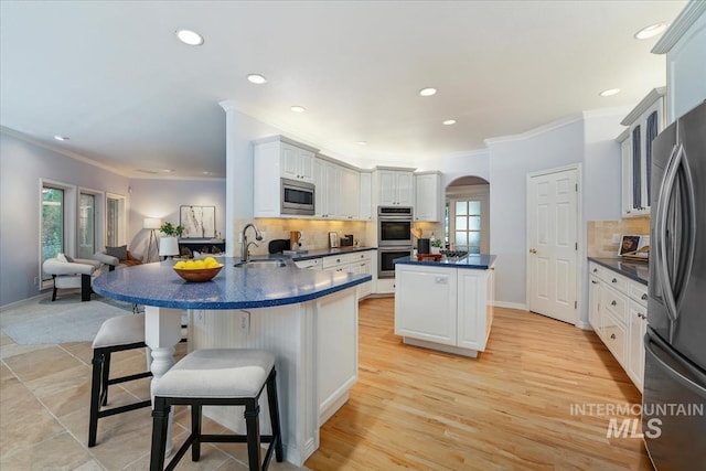 2368 SE 5th Way, Meridian, ID 83642 - kitchen with appliances with stainless steel finishes, ornamental molding, a kitchen island, dark countertops, and arched walkways