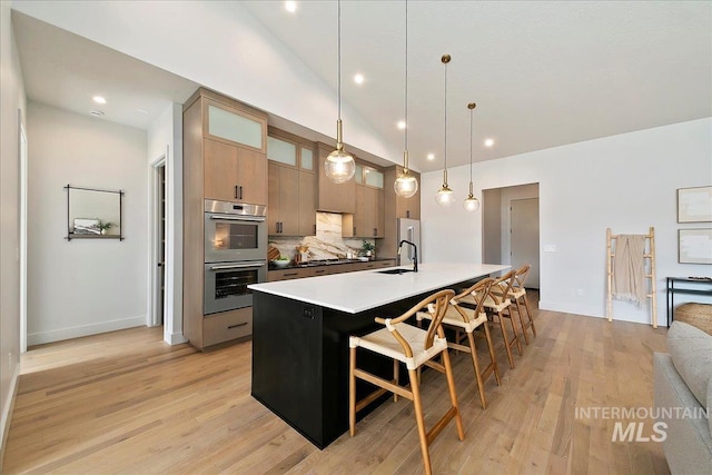 kitchen featuring backsplash, hanging light fixtures, sink, double oven, and a kitchen bar