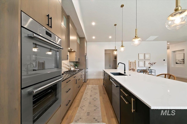 kitchen with a large island, sink, stainless steel appliances, tasteful backsplash, and pendant lighting