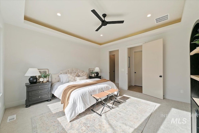 bedroom featuring ceiling fan, a raised ceiling, and light carpet