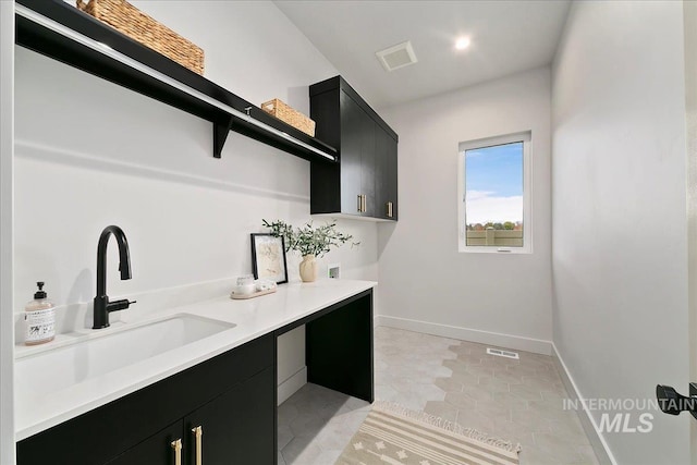 laundry area featuring hookup for a washing machine, sink, light tile patterned flooring, and cabinets