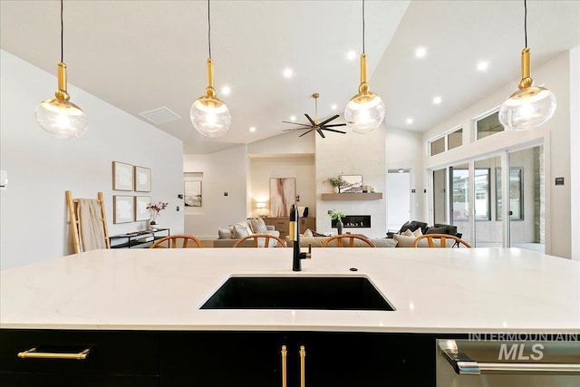 kitchen with a large fireplace, sink, pendant lighting, and lofted ceiling