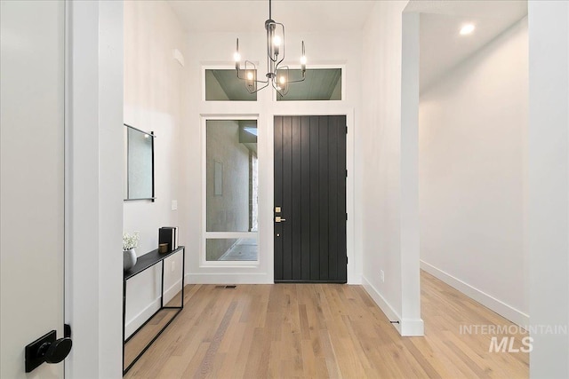 foyer entrance with light hardwood / wood-style floors and an inviting chandelier