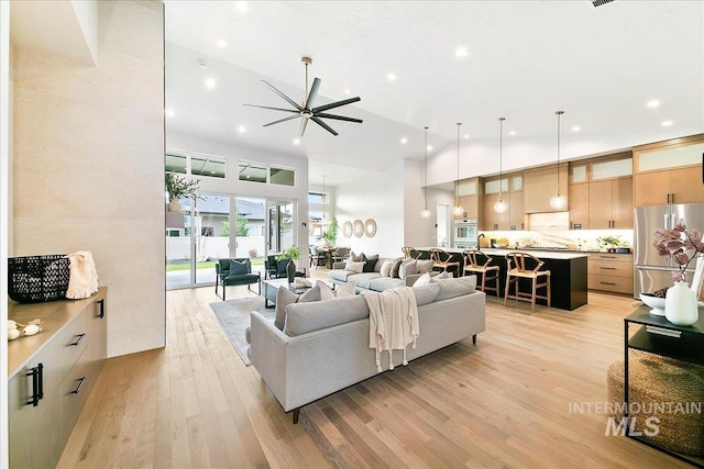 living room featuring ceiling fan, light hardwood / wood-style flooring, and high vaulted ceiling