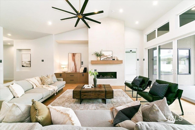 living room featuring ceiling fan, light hardwood / wood-style floors, and lofted ceiling