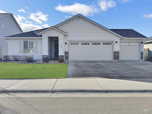 view of front of home with roof with shingles, concrete driveway, a front yard, a garage, and stone siding