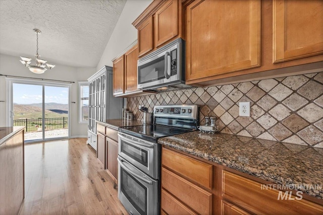 160 Summit Ridge Rd, Horseshoe Bend, ID 83629 - kitchen with stainless steel appliances, brown cabinets, decorative backsplash, light wood-style floors, and a textured ceiling