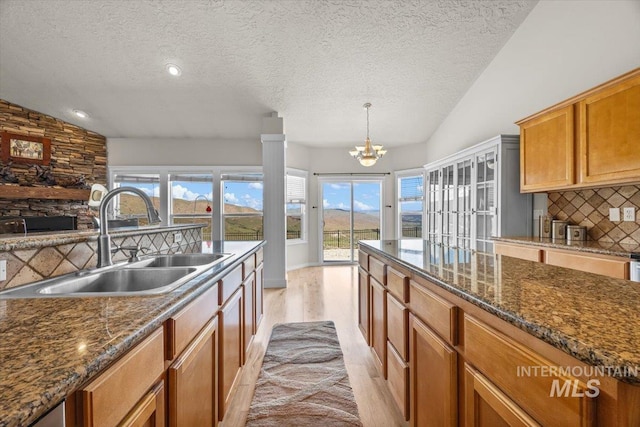 160 Summit Ridge Rd, Horseshoe Bend, ID 83629 - kitchen with a sink, vaulted ceiling, a textured ceiling, a fireplace, and decorative backsplash