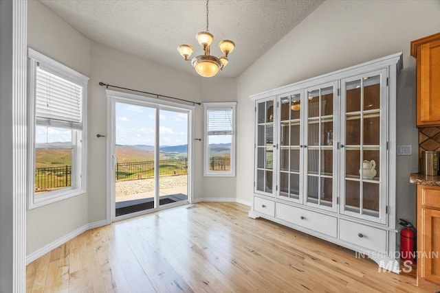 160 Summit Ridge Rd, Horseshoe Bend, ID 83629 - unfurnished dining area featuring a chandelier, vaulted ceiling, light wood-style flooring, a textured ceiling, and baseboards