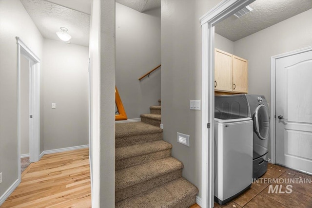 160 Summit Ridge Rd, Horseshoe Bend, ID 83629 - laundry area with cabinet space, washing machine and clothes dryer, a textured ceiling, baseboards, and light wood-style flooring