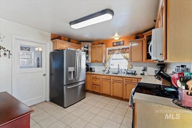 kitchen featuring sink, backsplash, stainless steel fridge, and light tile patterned flooring