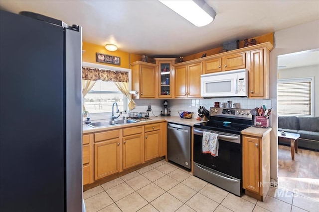 kitchen featuring tasteful backsplash, sink, stainless steel appliances, and light tile patterned flooring