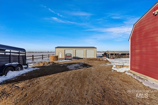 yard covered in snow with a garage and an outdoor structure