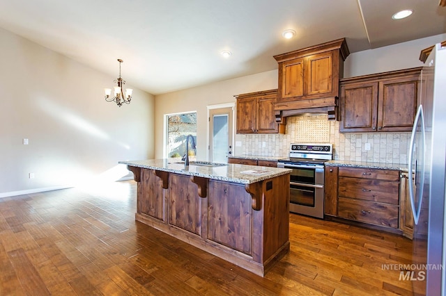 kitchen with sink, hanging light fixtures, light stone counters, a kitchen bar, and appliances with stainless steel finishes