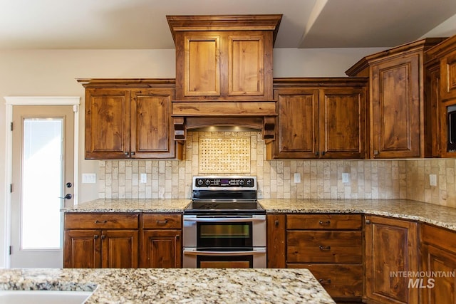 kitchen with decorative backsplash, stainless steel electric range oven, light stone countertops, and custom exhaust hood