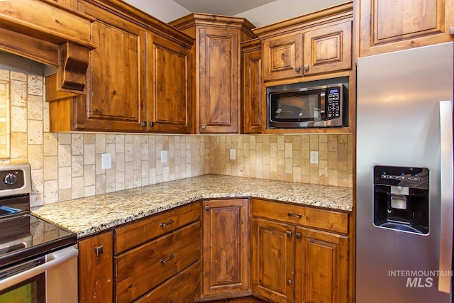 kitchen with backsplash, light stone countertops, and stainless steel appliances